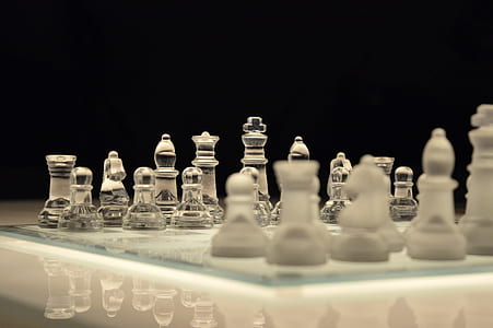 Clear Glass and White Chess Piece on White Chess Board With Black Background