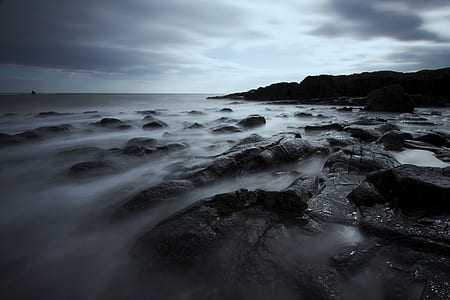 long-exposure body of water and gray rocks at daytime