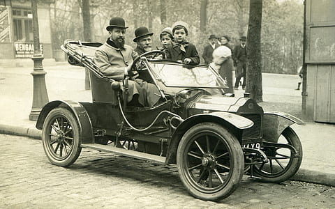 grayscale photography of group of people on antique car
