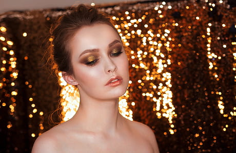 woman with brown eyeshadow near string lights