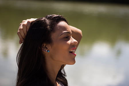 selective focus photography of woman smiling holding her hair