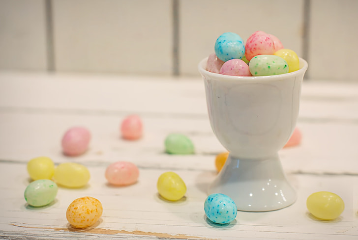 egg candies surrounded beside ceramic footed cup