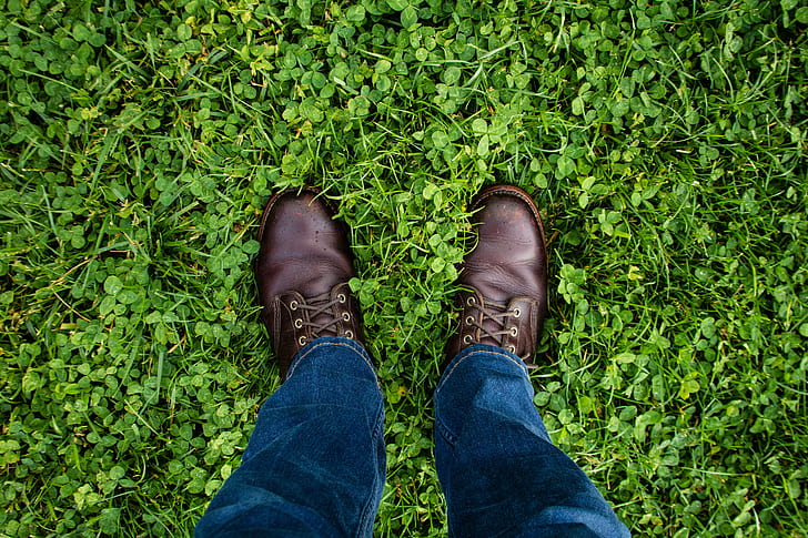 man wearing blue jeans and brown leather shoes standing on green field