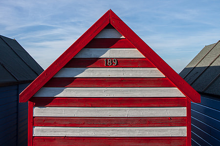 A red and white-striped beach hut sits on the Kent Coast in Southern England