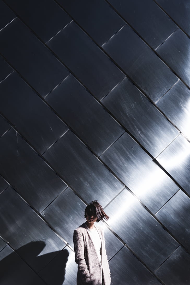 woman wearing gray coat standing near wall