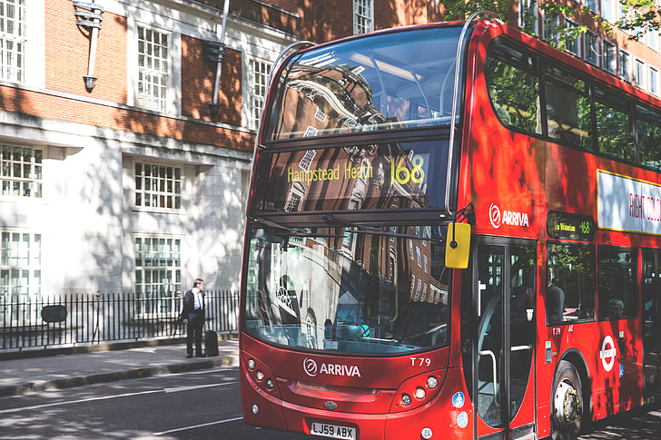 A classic red London bus sits in dappled sunlight on a road in Central London, image captured with a Canon DSLR