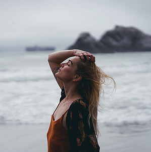 woman holding her hair near sea shore