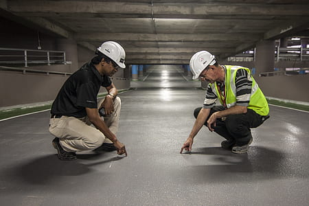 two men pointing grey floor inside underground
