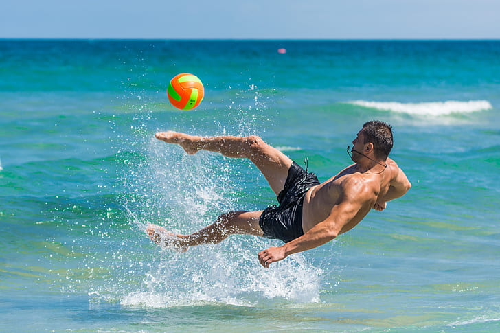 man kicked ball on body of water