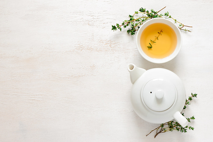 white ceramic teapot beside teacup with tea