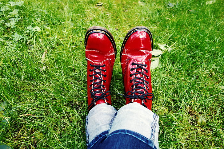 person wearing pair of leather boots sitting on grass