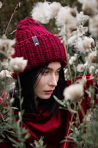 closeup photo of woman wearing knit cap surrounded by dandelion flowers