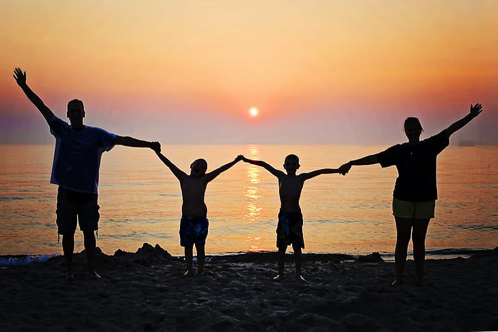 family silhouette on seashore during sunset