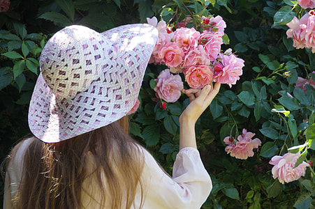 woman wearing sun hat holding flowers
