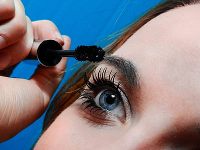 woman putting mascara on her lashes