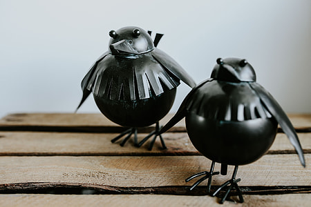 Little black plastic birds with a smartphone on a shelf