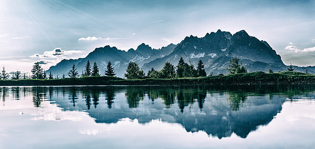 body of water surrounding mountain and trees