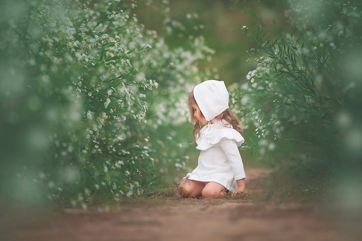 selective focus photography of girl wearing white dress lying between green leaf plants at daytime