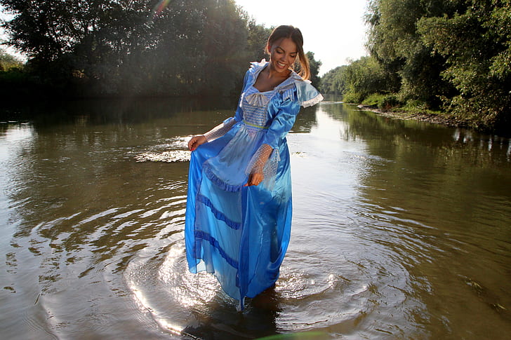 woman wearing blue dress standing on body of water during day time