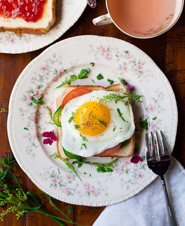 friend egg on bread on white ceramic plate beside stainless steel fork