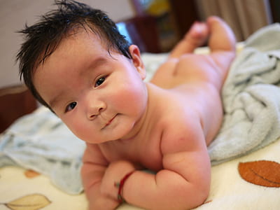 photography of naked baby on gray towel