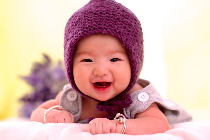 baby in grey clothes wearing purple knitted hat