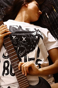woman in white and black crew-neck shirt holding brown electric guitar