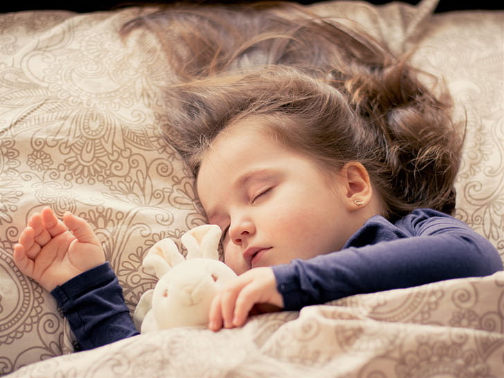 girl sleeping beside bunny plush toy during daytime