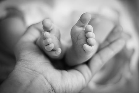grayscale photo of person holding baby's feet