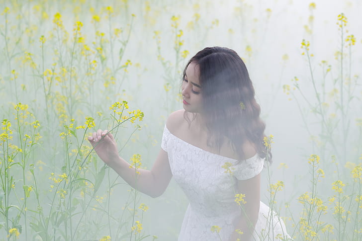 woman wearing white off-shoulder dress holding yellow flower