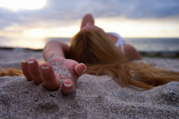 shallow photography of woman holding sand during daytime
