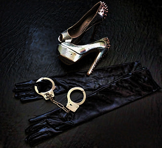 photo of pair of gold-colored spike studded sandals, handcuffs, and spandex gloves both on black surface