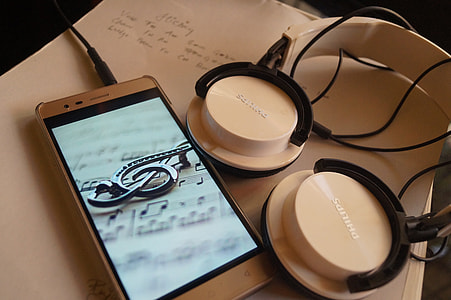 white Philips headphones beside smartphone