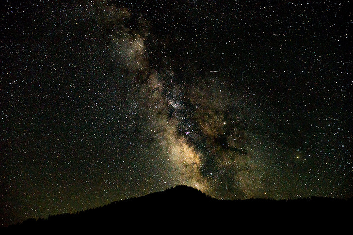 silhouette mountain under milky way sky at night time