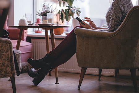 photo of woman sitting on sofa chair using smartphone