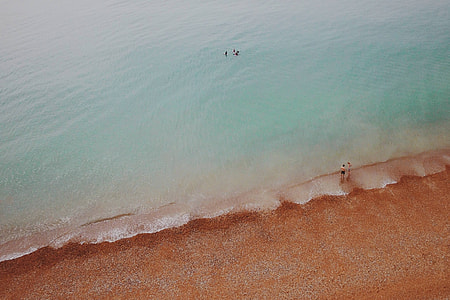 aerial photo of two person standing on seashore during daytime