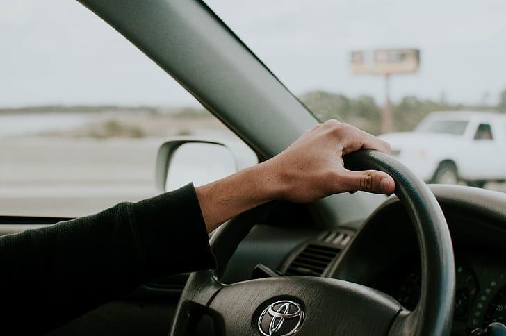 person holding black Toyota steering wheel inside car