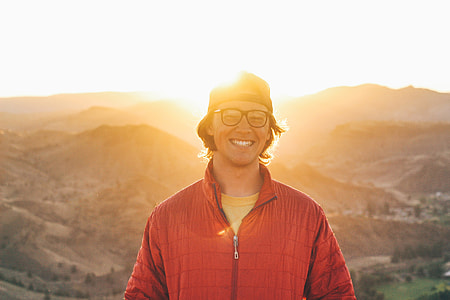 Man in glasses with smile standing in the sunlit mountains