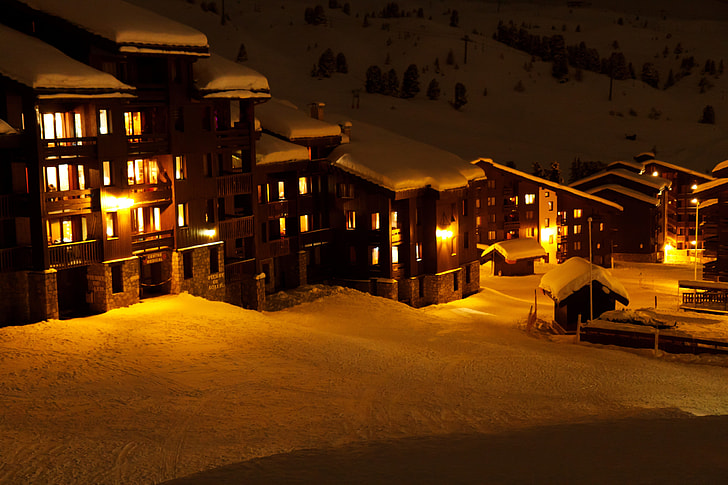 lighted village houses surrounded of snow covered field during nighttime