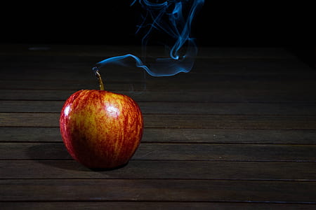 Red Apple With Smoke Coming from Stalk on Wooden Floor