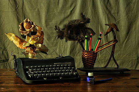 black typewriter beside wicker brown pen holder above table