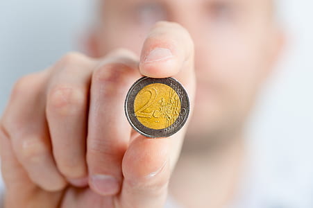 person holding round silver and gold-colored 2 coin
