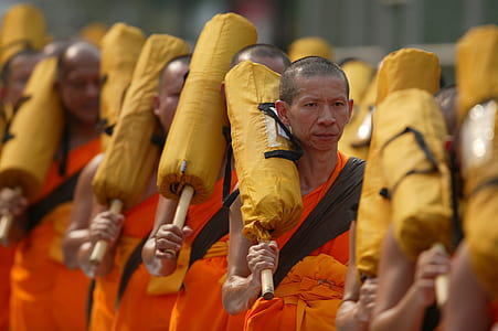 monks holding yellow bags forming line