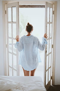 woman standing on door holding open door wearing white dress shirt