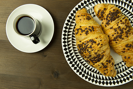 Overhead shot of coffee cup and croissants on a wood table