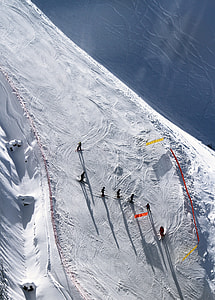 group of people skiing on snow near body of water during daytime