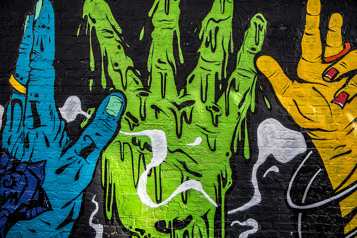 Street art depicting vibrantly coloured hands captured on a brick wall