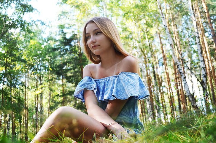 woman wearing blue and white strapless top sitting on green grasses