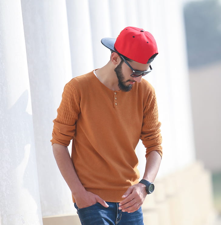 man wearing orange long-sleeved shirt and red cap