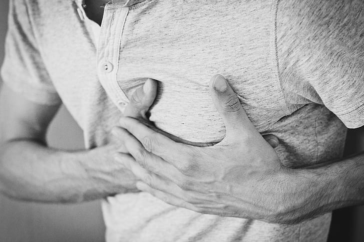 man holding chest grayscale photo